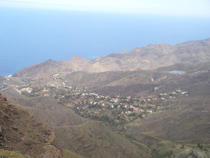 Vista de Alojera, rodeada de bancales y palmerales, en medio de un agreste paisaje